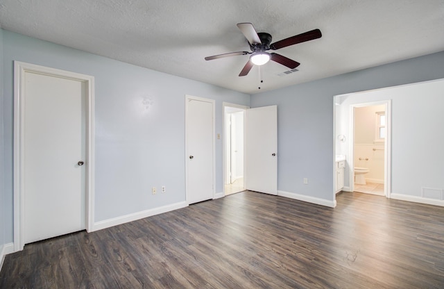 unfurnished bedroom featuring visible vents, dark wood finished floors, a textured ceiling, and baseboards