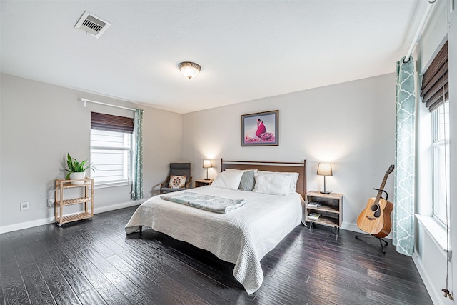 bedroom with baseboards, visible vents, and dark wood finished floors