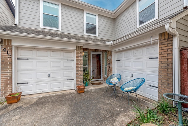 doorway to property featuring brick siding and an attached garage