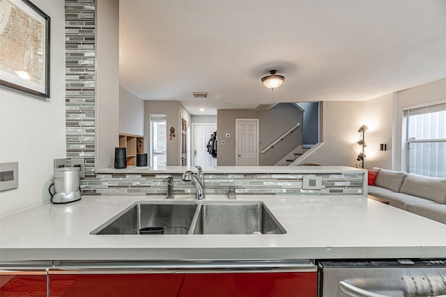 kitchen featuring a sink, visible vents, open floor plan, stainless steel dishwasher, and backsplash