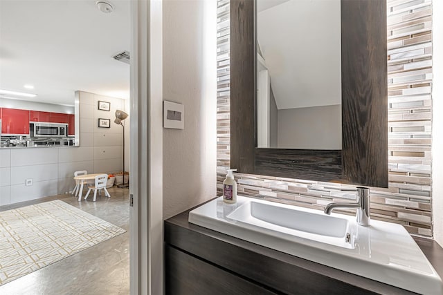 bathroom with tasteful backsplash, visible vents, and concrete flooring