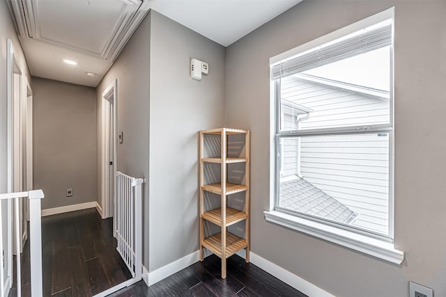 hall with attic access, dark wood-type flooring, and baseboards