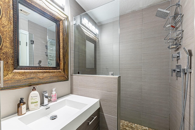 full bathroom featuring visible vents, vanity, and walk in shower