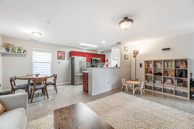 interior space featuring tasteful backsplash, baseboards, appliances with stainless steel finishes, open floor plan, and a peninsula