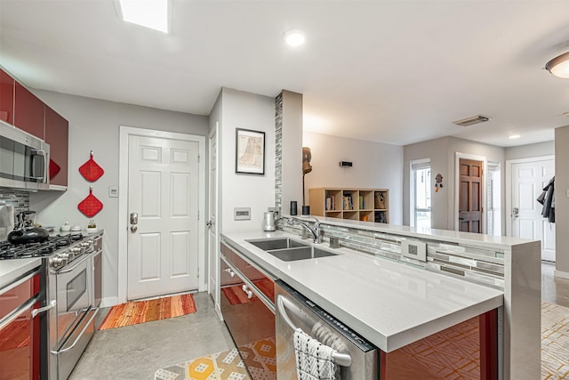 kitchen with a peninsula, appliances with stainless steel finishes, light countertops, and a sink