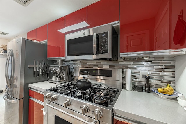 kitchen featuring stainless steel appliances, visible vents, light countertops, red cabinets, and decorative backsplash