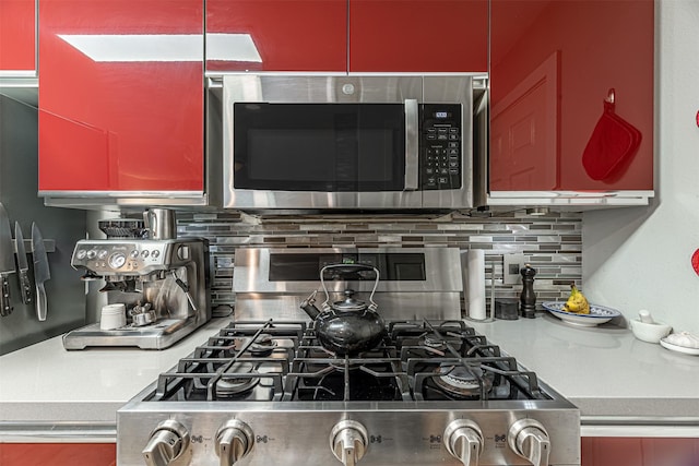 kitchen with tasteful backsplash, stainless steel microwave, light countertops, and red cabinets