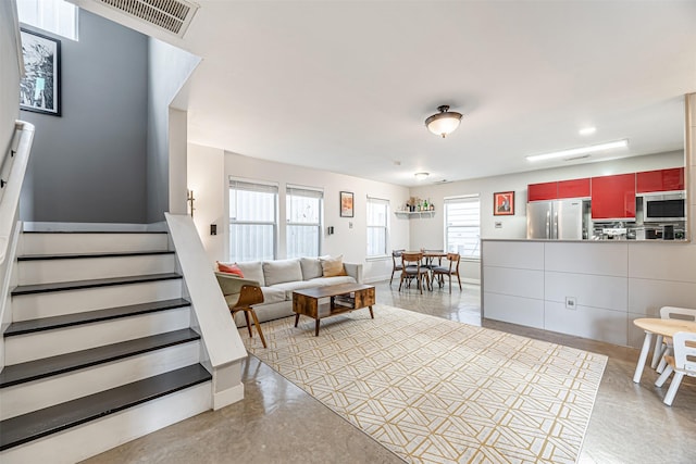 living room with baseboards, stairs, visible vents, and concrete flooring