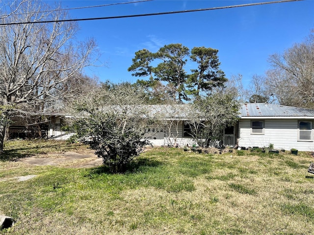 back of property with metal roof and a lawn