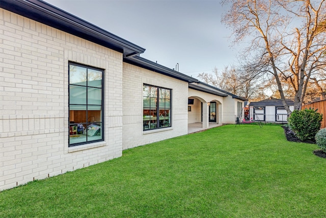 view of yard featuring an outbuilding, a storage unit, a patio, and fence