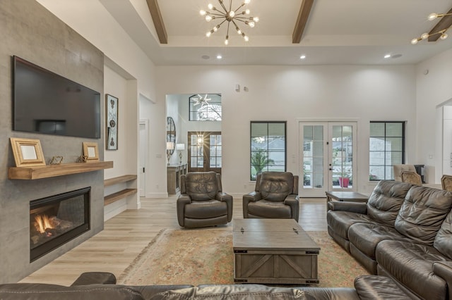 living area with french doors, a high ceiling, beamed ceiling, and a fireplace