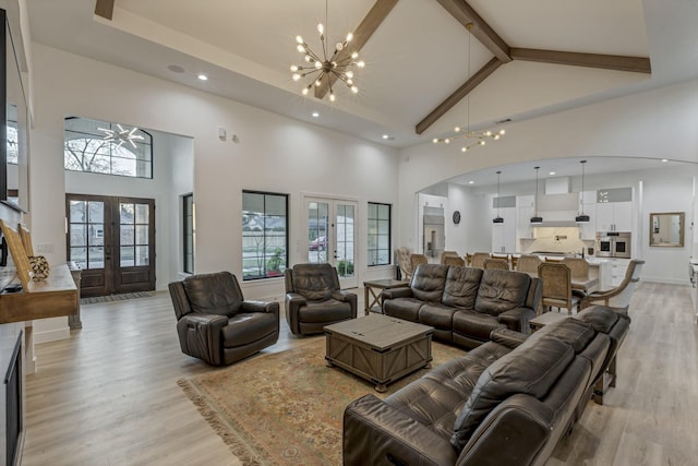 living room featuring high vaulted ceiling, beam ceiling, french doors, a notable chandelier, and light wood-type flooring