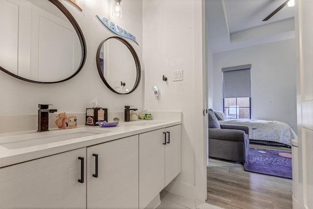 ensuite bathroom with double vanity, wood finished floors, ensuite bathroom, and a sink