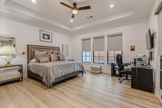 bedroom with a tray ceiling, recessed lighting, baseboards, and light wood-type flooring