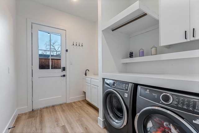 laundry area featuring baseboards, cabinet space, light wood-style floors, and washer and clothes dryer