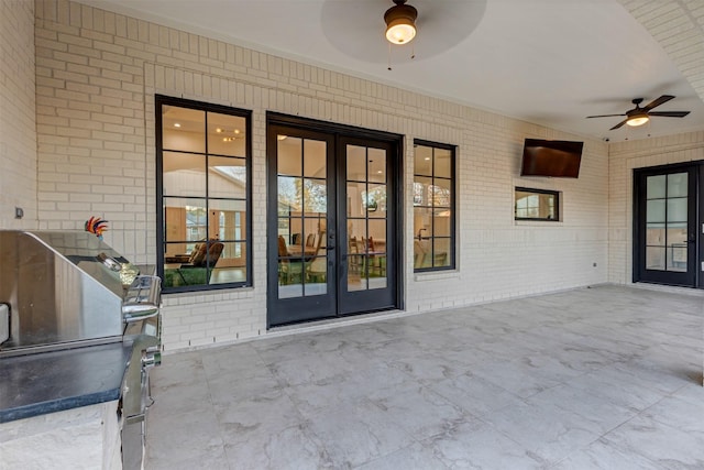 property entrance featuring brick siding, a patio area, french doors, and a ceiling fan