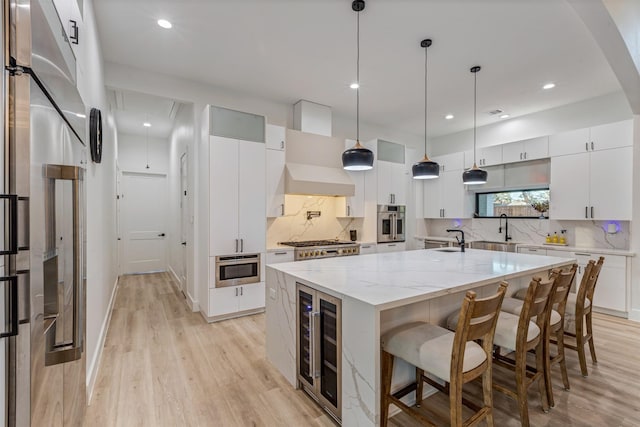 kitchen with wine cooler, light wood-type flooring, appliances with stainless steel finishes, and a sink