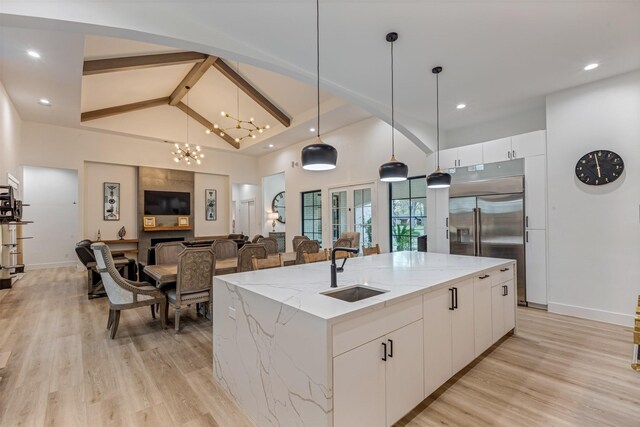 kitchen featuring light wood-type flooring, pendant lighting, a sink, built in fridge, and white cabinets