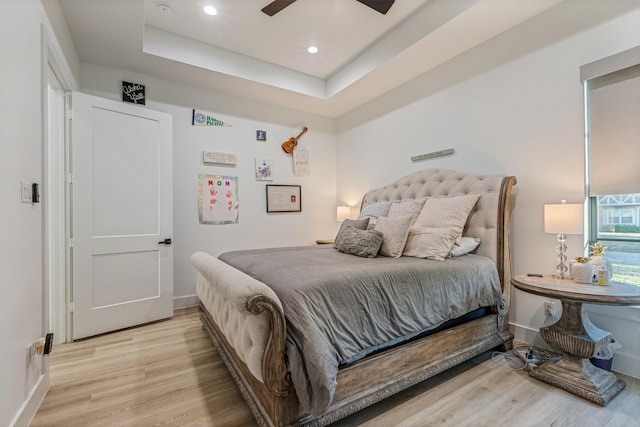 bedroom featuring a raised ceiling, recessed lighting, baseboards, and light wood-type flooring