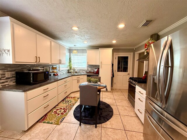 kitchen featuring a sink, visible vents, ornamental molding, appliances with stainless steel finishes, and dark countertops