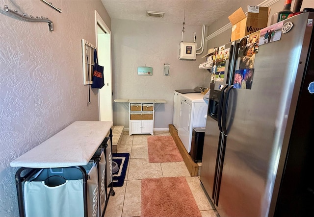 kitchen featuring a textured wall, light tile patterned flooring, visible vents, independent washer and dryer, and stainless steel fridge with ice dispenser