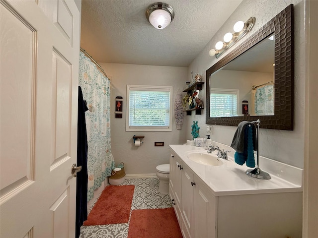 bathroom featuring toilet, a textured ceiling, vanity, baseboards, and tile patterned floors