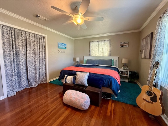 bedroom with ornamental molding, wood finished floors, and visible vents