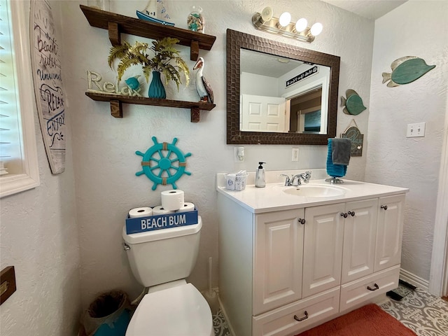 bathroom with toilet, a textured wall, and vanity