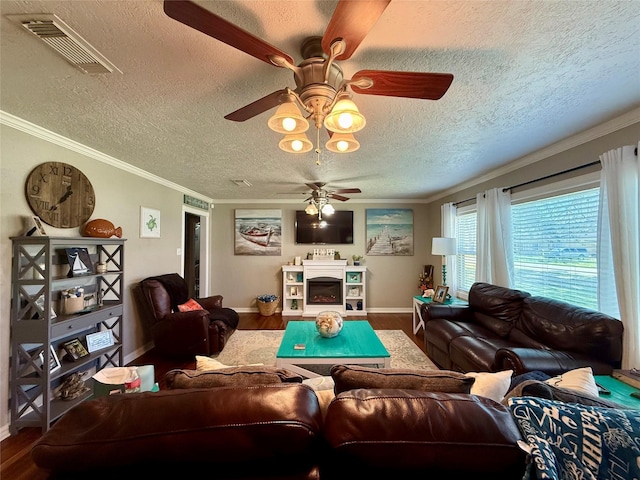 living room featuring baseboards, visible vents, ornamental molding, wood finished floors, and a fireplace