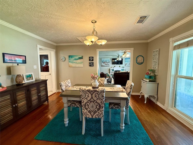 dining space featuring a textured ceiling, visible vents, baseboards, dark wood finished floors, and crown molding