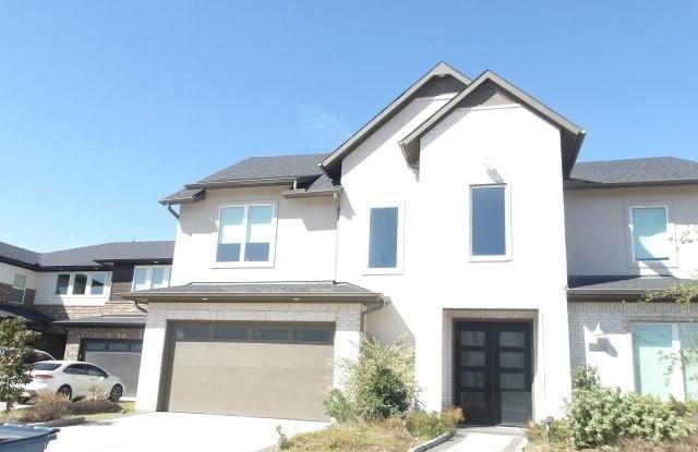 view of front of property featuring a garage, brick siding, driveway, and stucco siding