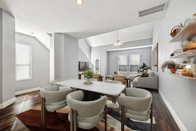 dining space featuring visible vents, baseboards, lofted ceiling, dark wood-style floors, and a ceiling fan