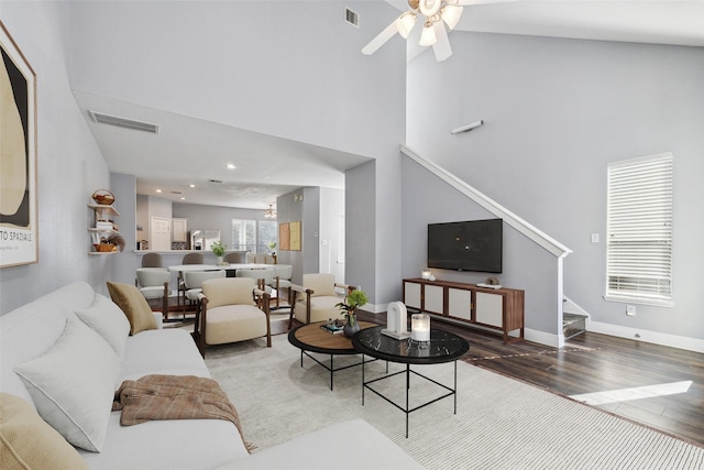 living room with visible vents, baseboards, wood finished floors, and stairs