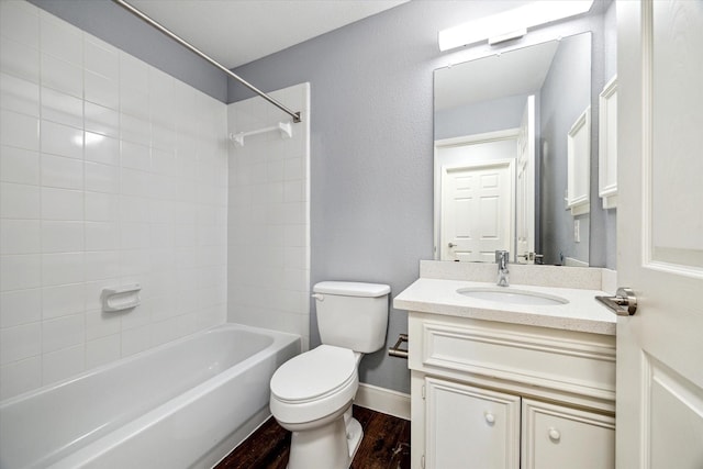 bathroom with baseboards, toilet, bathing tub / shower combination, wood finished floors, and vanity