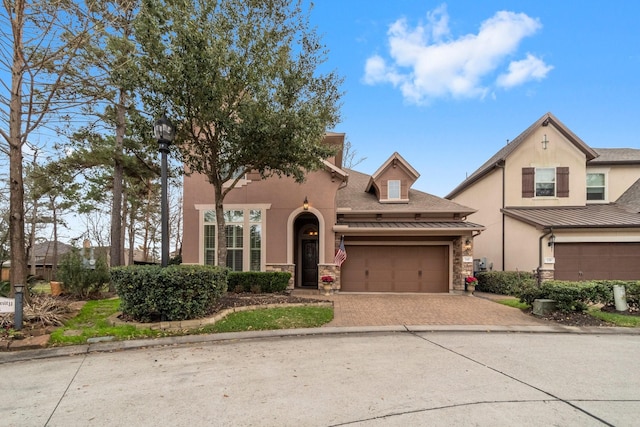 view of front of property with a garage, stone siding, decorative driveway, and stucco siding