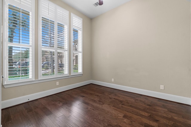 spare room featuring a healthy amount of sunlight, dark wood finished floors, and baseboards