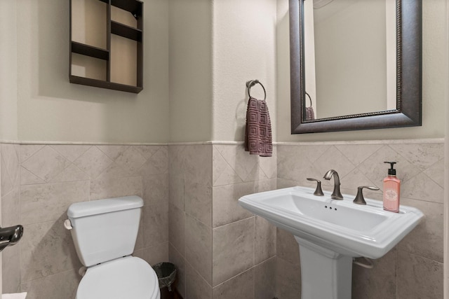 bathroom with toilet, a wainscoted wall, and tile walls