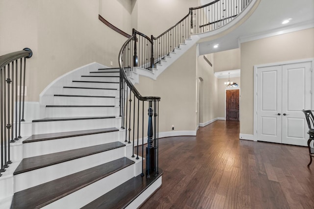 entryway with baseboards, a towering ceiling, stairway, wood finished floors, and an inviting chandelier