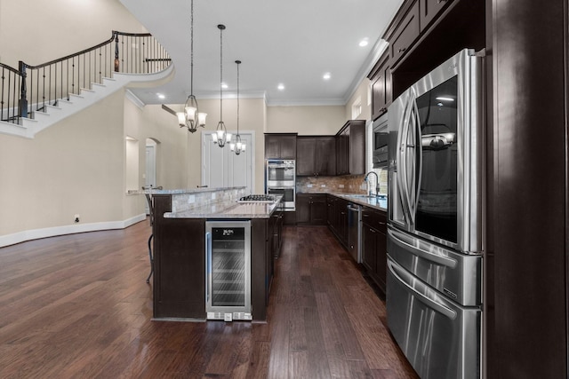 kitchen featuring beverage cooler, stainless steel appliances, a kitchen island, a sink, and tasteful backsplash