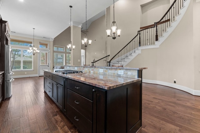 kitchen with a towering ceiling, appliances with stainless steel finishes, a chandelier, and dark wood-style flooring