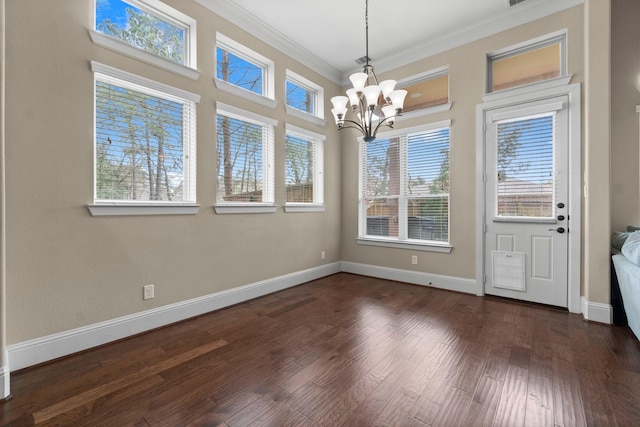 unfurnished dining area with ornamental molding, dark wood-style flooring, baseboards, and an inviting chandelier