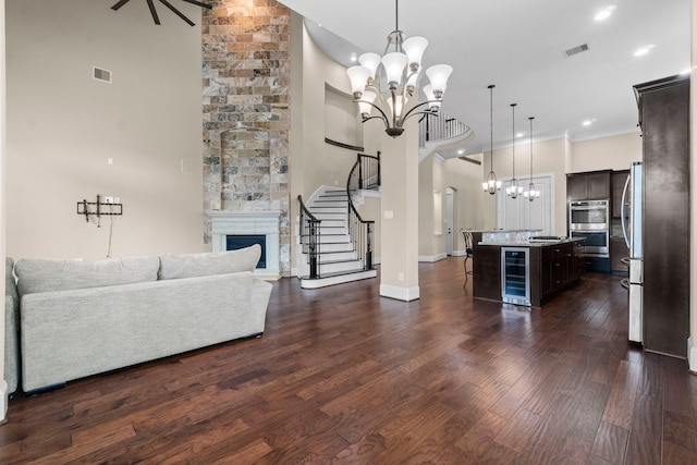 unfurnished living room with a large fireplace, beverage cooler, dark wood-type flooring, and a notable chandelier