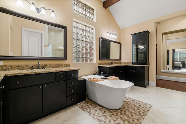 full bathroom with vaulted ceiling with beams, a soaking tub, tile patterned flooring, and a sink