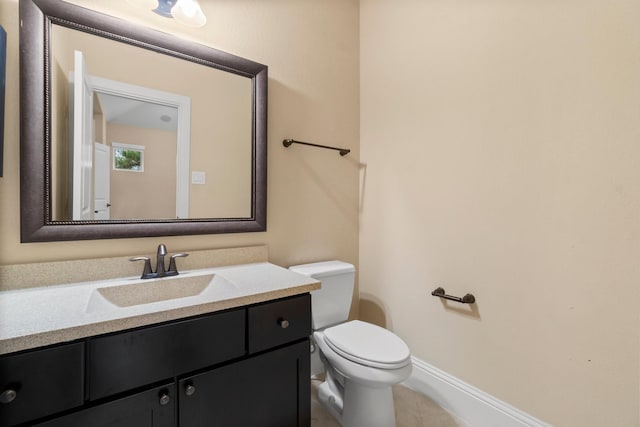 half bathroom with tile patterned flooring, vanity, toilet, and baseboards