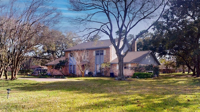 view of front of property with a front lawn, a chimney, and brick siding