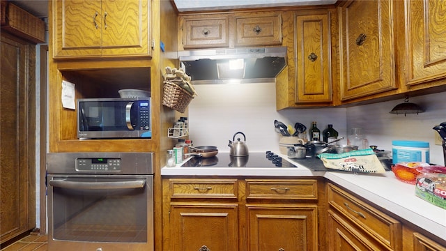 kitchen featuring stainless steel appliances, range hood, light countertops, and brown cabinetry