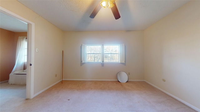 empty room with carpet floors, a textured ceiling, baseboards, and a ceiling fan