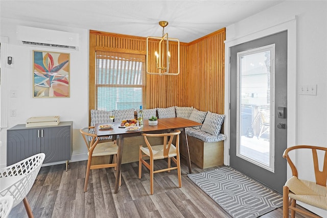 dining area featuring breakfast area, a wealth of natural light, a wall unit AC, and wood finished floors