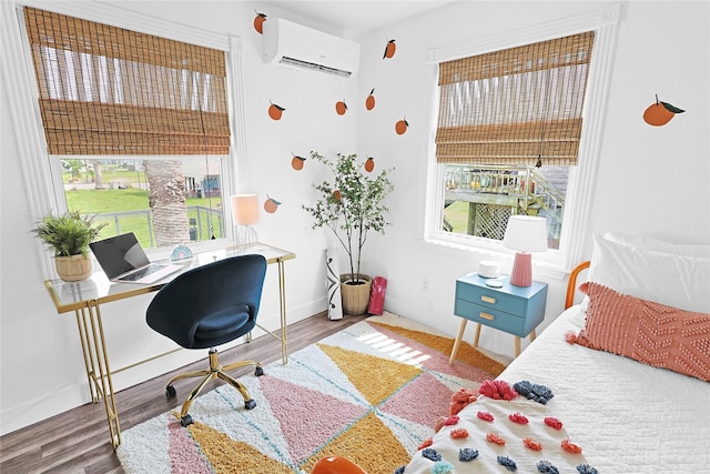 bedroom with wood finished floors, baseboards, and a wall mounted AC