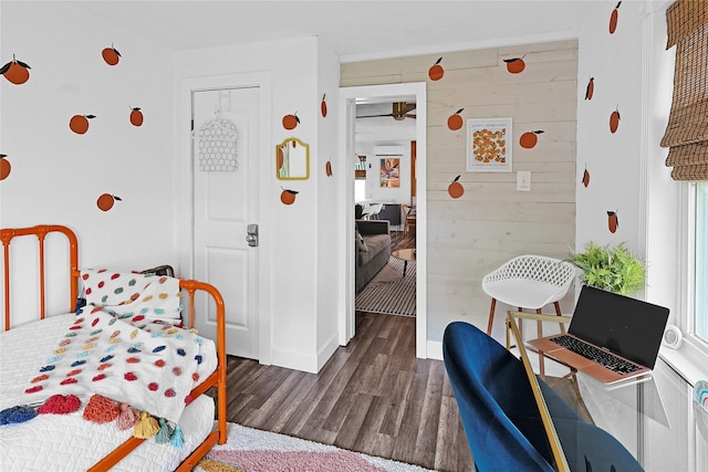 bedroom with wood walls, wood finished floors, and baseboards